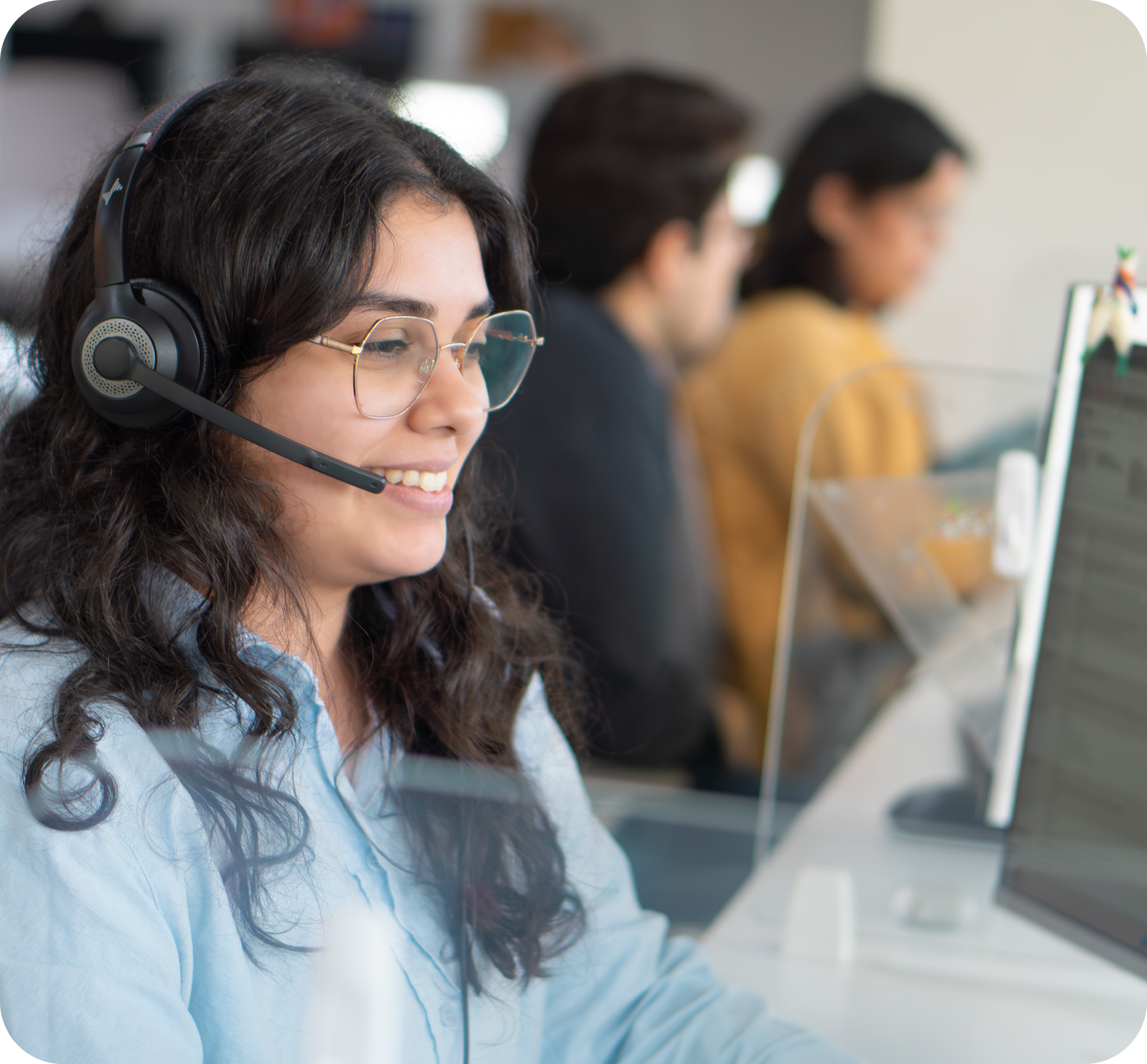 Work Ninjas call agent with headset and glasses, softly blurred call-center bullpen behind her