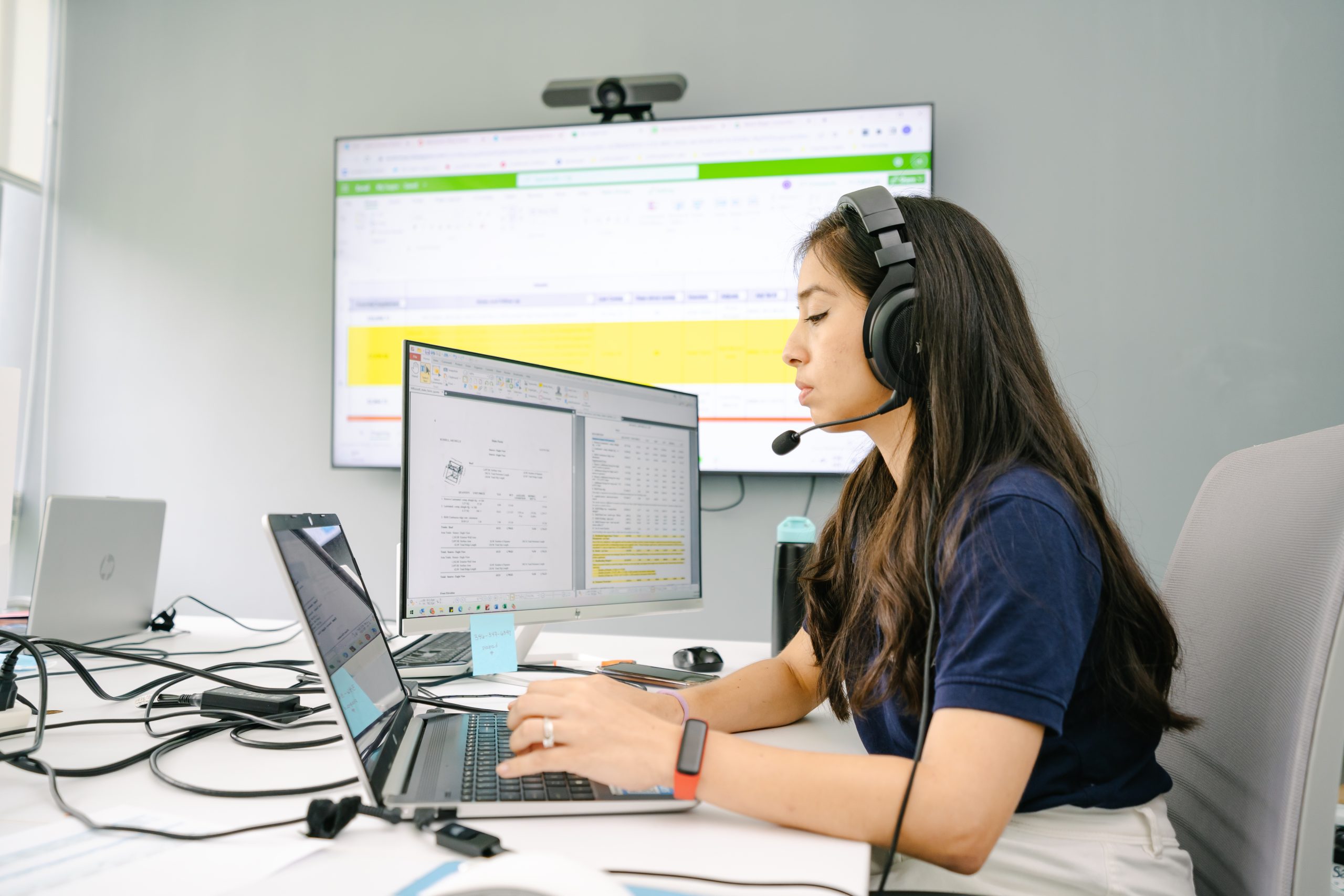 Work Ninjas supplements specialist at a triple-monitor desk running Xactimate paperwork